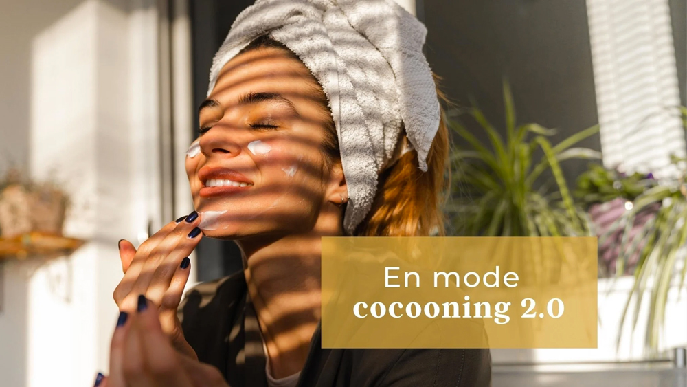 Femme avec les cheveux enroulés dans une serviette qui s'applique de la crème sur le visage